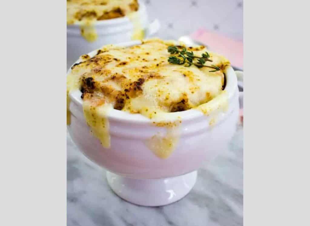 Two bowls of French onion soup with thyme on top.