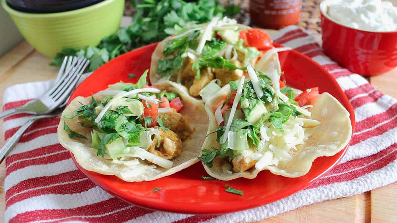 Fried chicken tacos on a red plate.