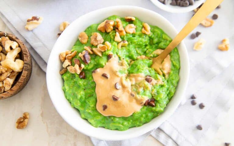 A bowl of green oatmeal with peanut butter and chocolate chips.