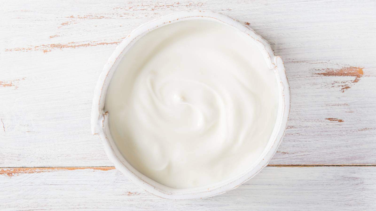 A picture of homemade yogurt in bowl on while wood background.