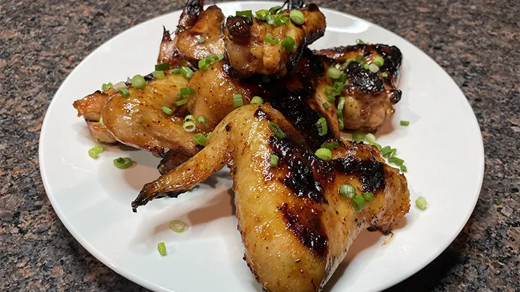 Grilled honey mustard chicken wings on white plate.