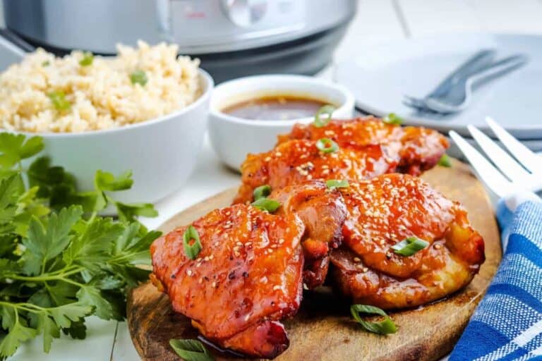 Instant pot teriyaki chicken on a cutting board with rice.