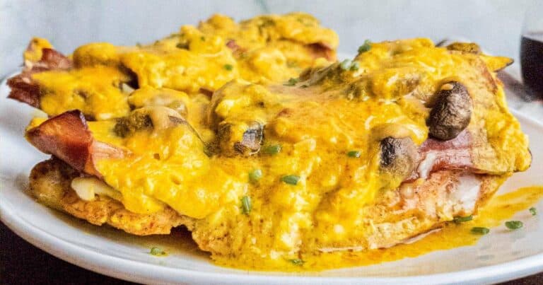A plate with a chicken covered in cheese and mushrooms.