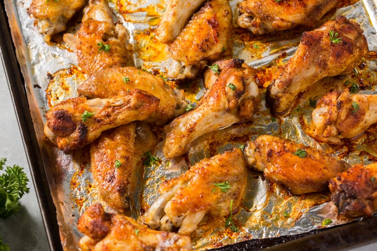 Keto chicken wings on a cookie sheet topped with parsley.