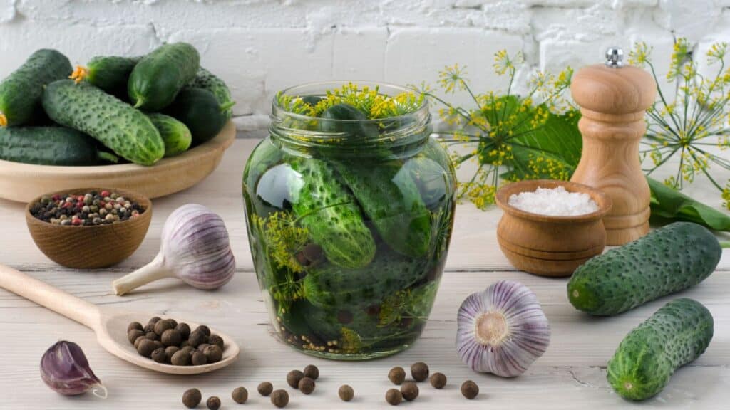 A mouthwatering jar of pickles, garlic and herbs on a rustic wooden table.