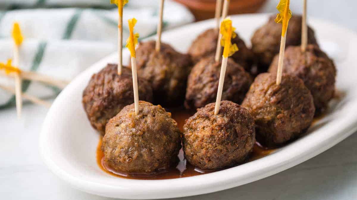 Plate of frozen meatballs with toothpicks sticking out of them.