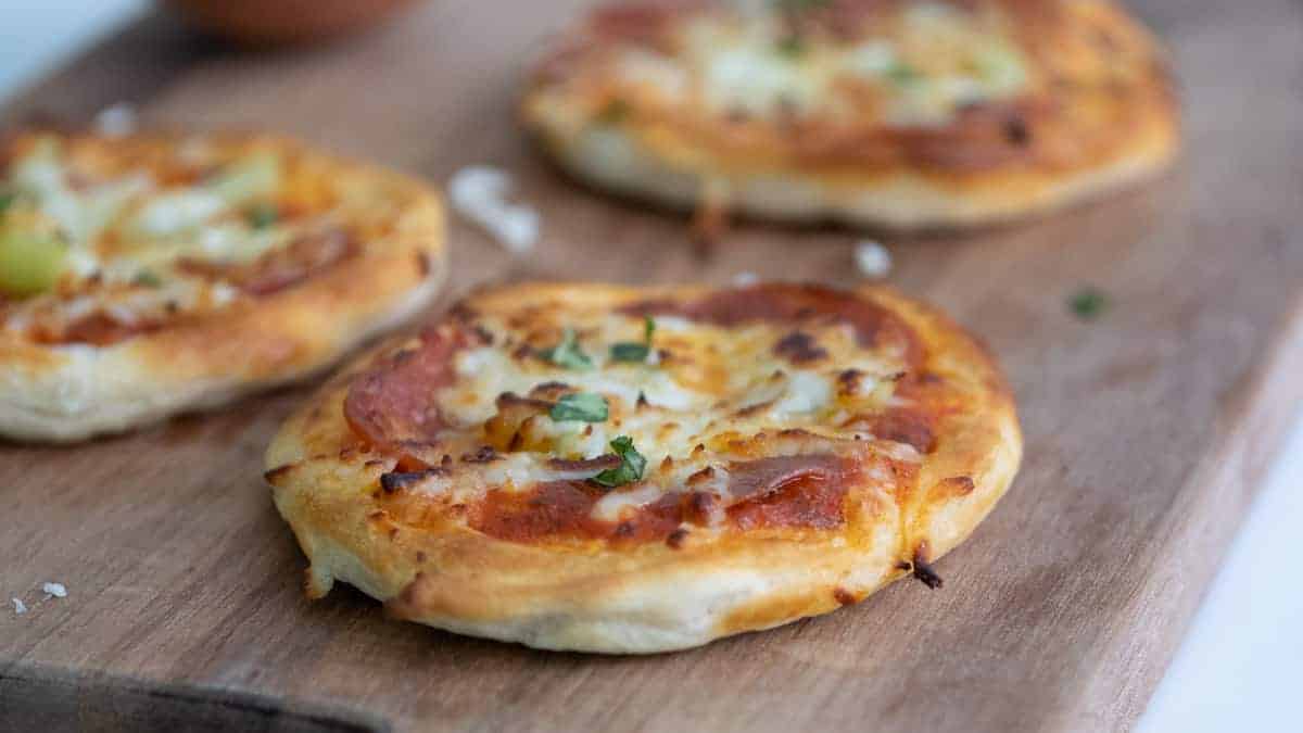 3 biscuit pizzas on a cutting board.