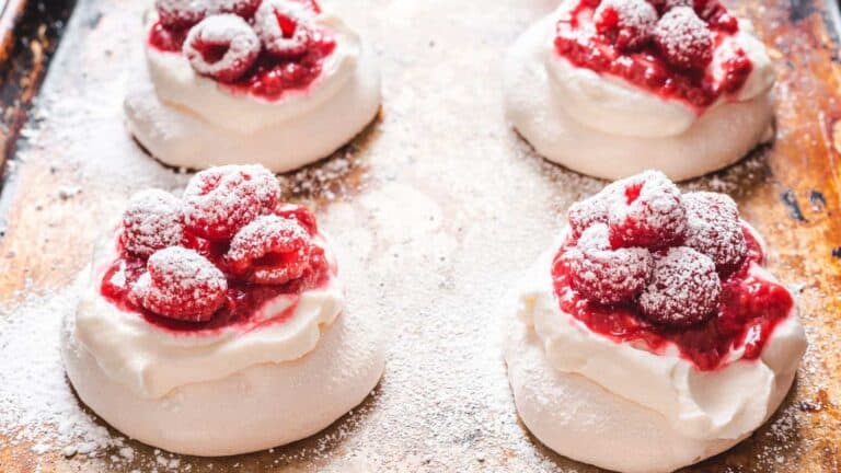 A few raspberry pavlovas on a baking sheet.