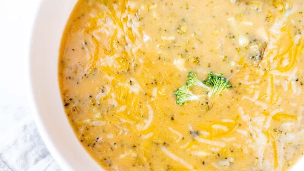 Cheesy broccoli soup in a white bowl.