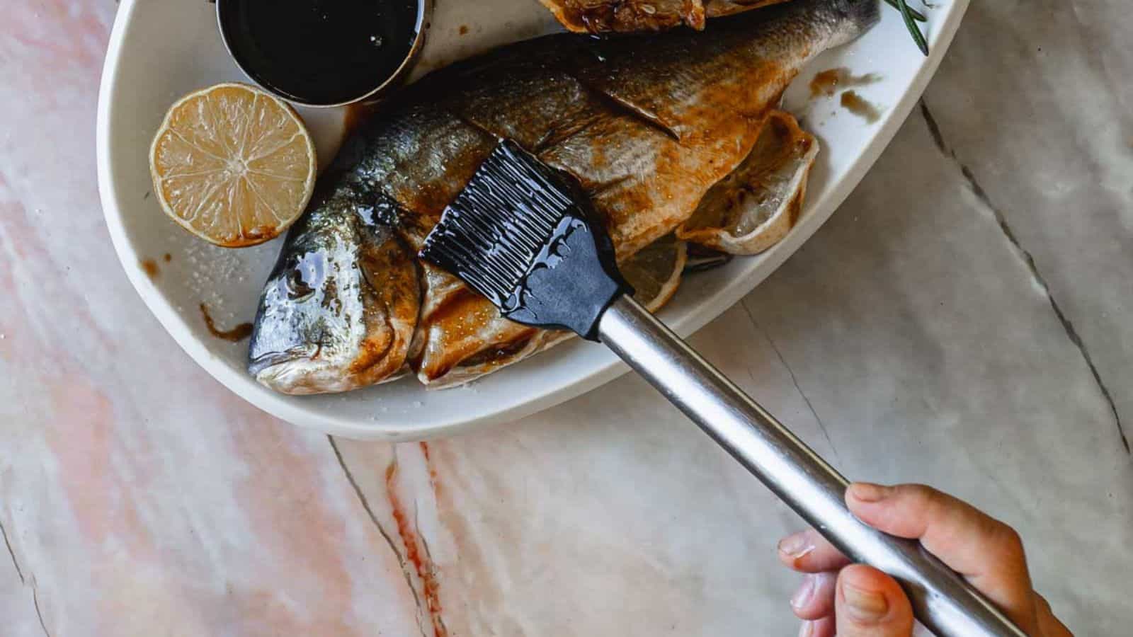 A person painting a fish on a plate.