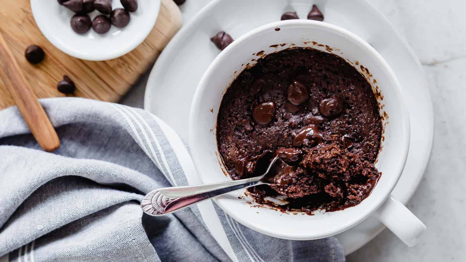 Chocolate protein mug cake in a white bowl with a spoon.