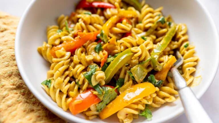 A bowl of pasta with vegetables and a fork.