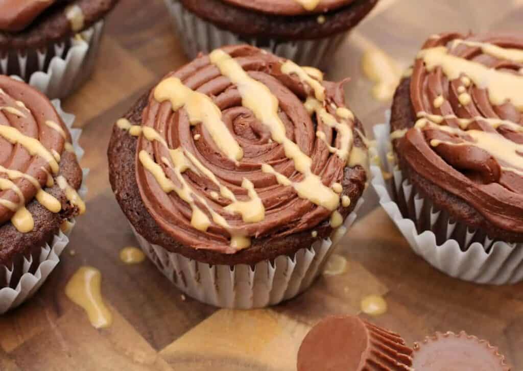 Chocolate cupcakes with peanut butter frosting on a cutting board.