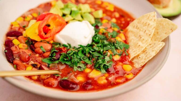A slow cooker mexican bean and corn soup with sour cream and avocado.