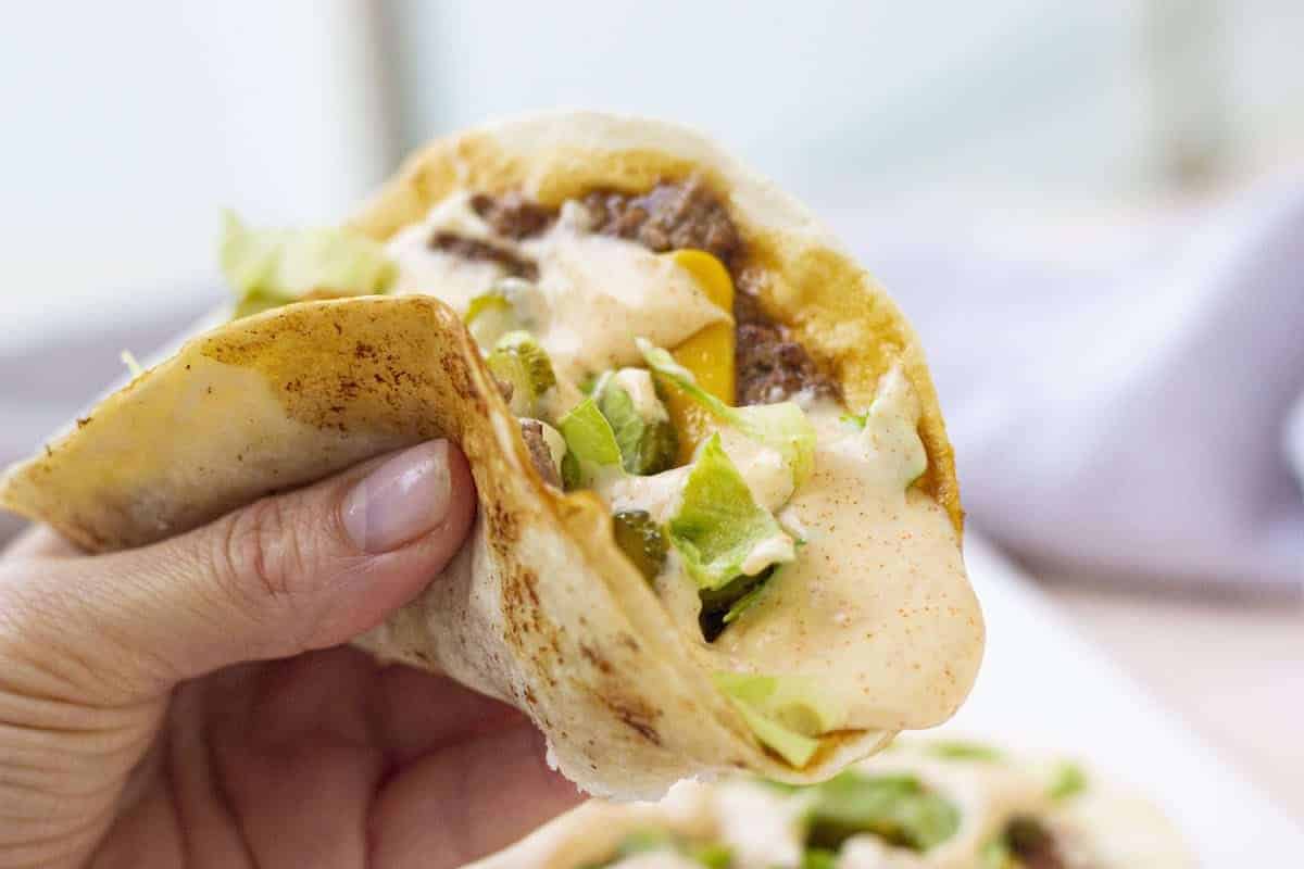 Flat taco on a white plate on a blue background.