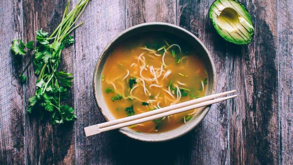 A bowl of avocado noodle soup served with chopsticks is a delicious and affordable dinner option.