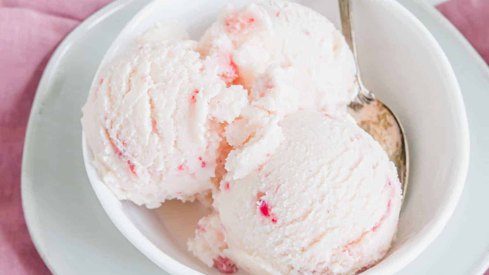 Strawberry kefir ice cream in a white bowl with a silver spoon.