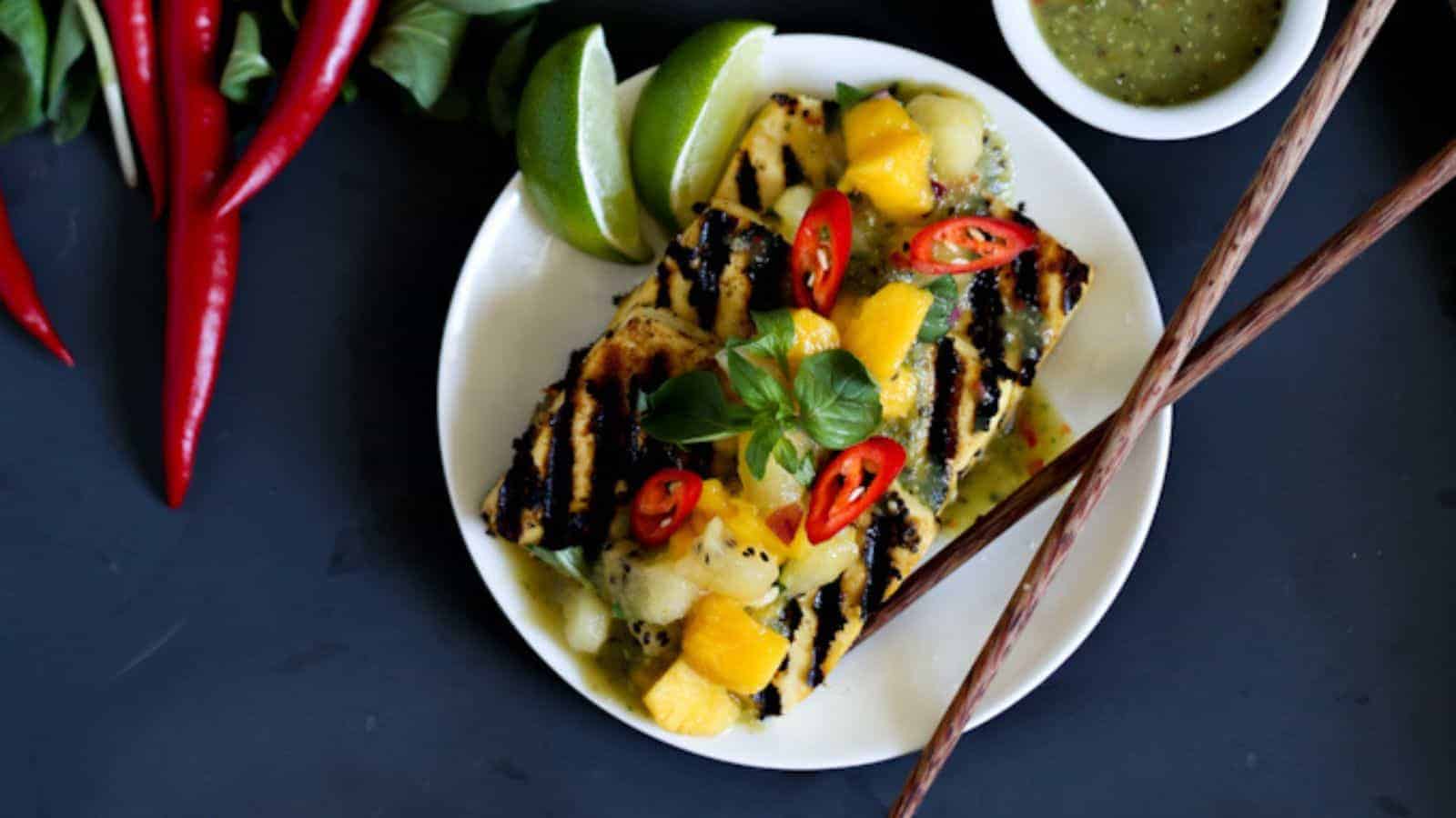 A plate of grilled tofu with mango sauce and chopsticks.