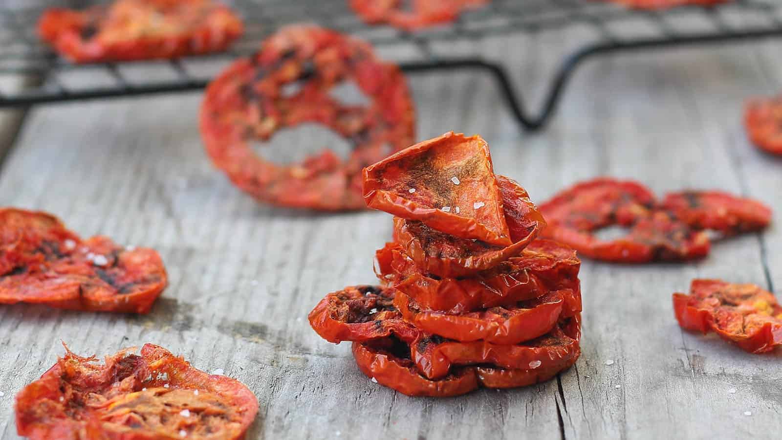 Tomato chips stacked on a white surface.