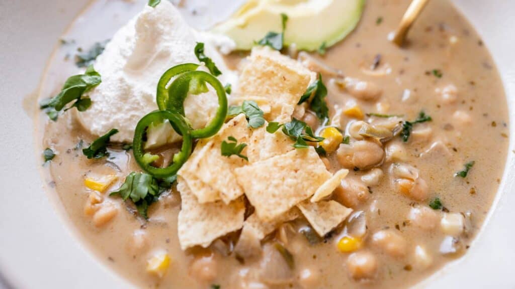 A bowl of mexican bean soup with sour cream and guacamole.