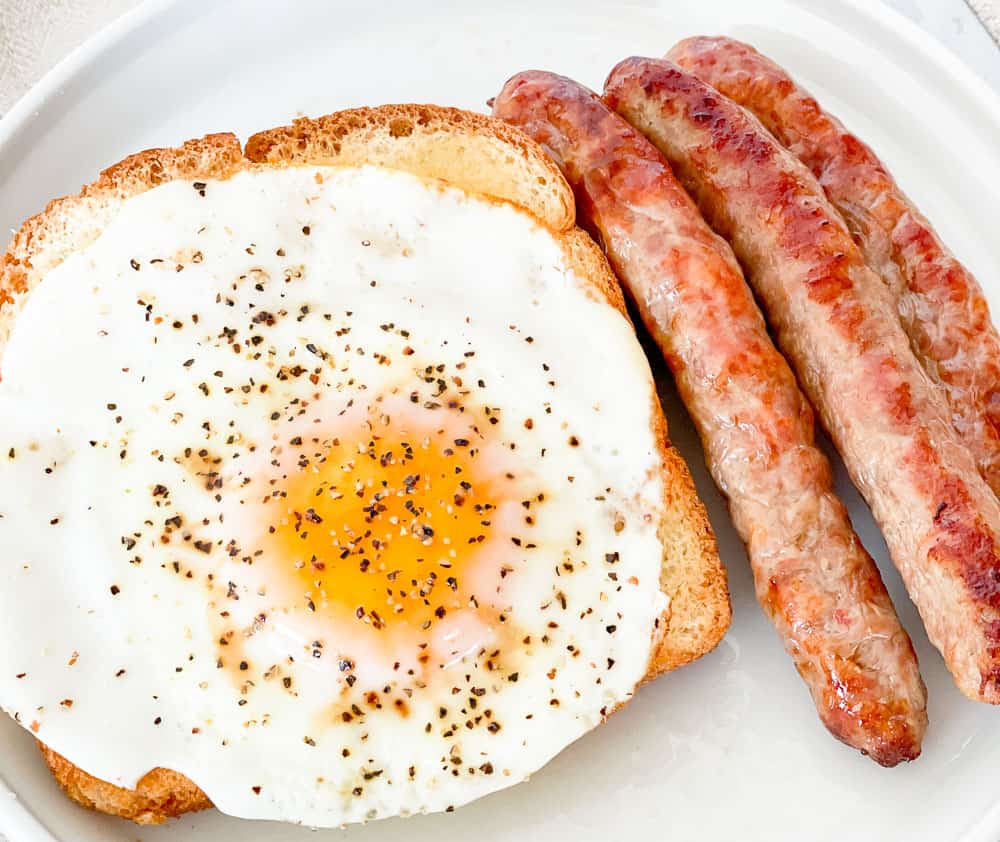A plate with sausages and an egg on it.