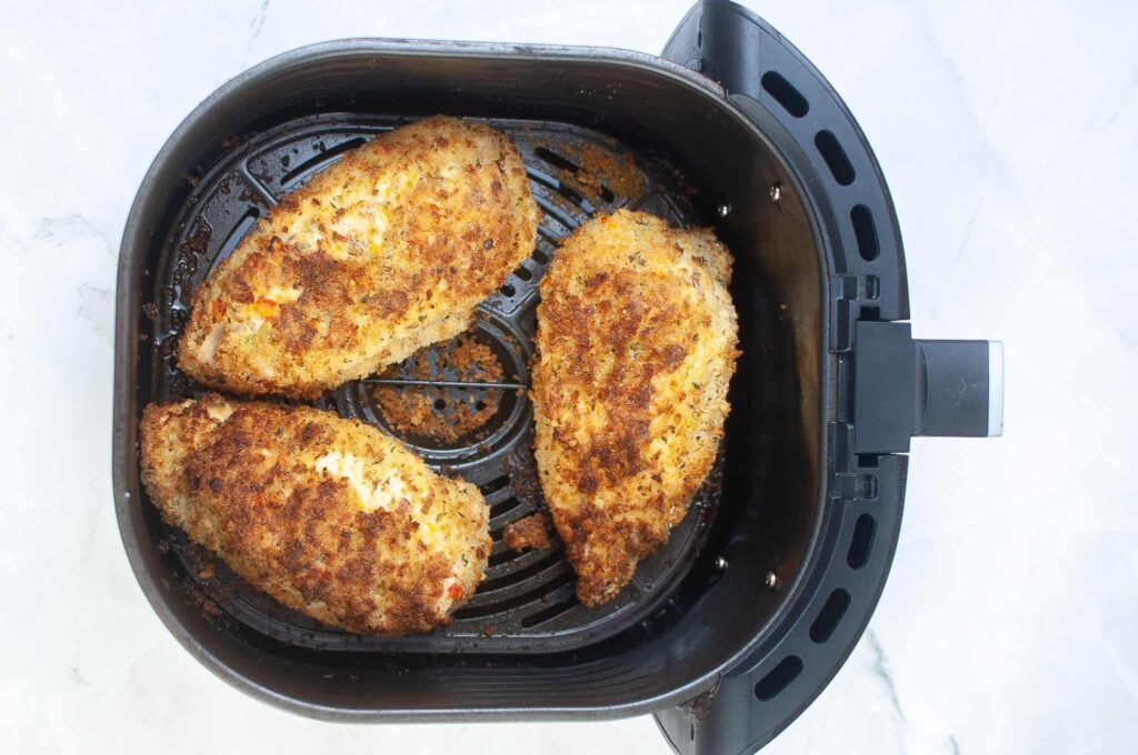 Two chicken breasts in an air fryer.