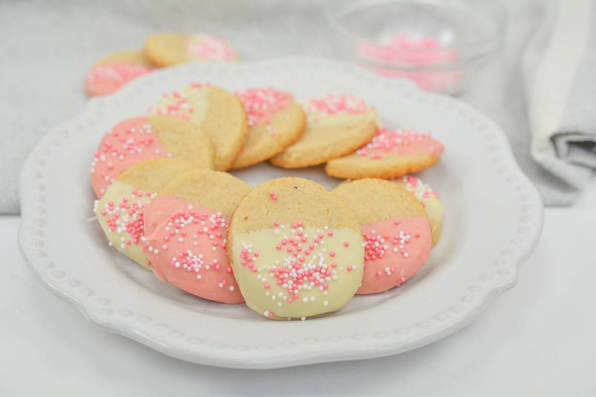 A plate of pink and white cookies with sprinkles on it.