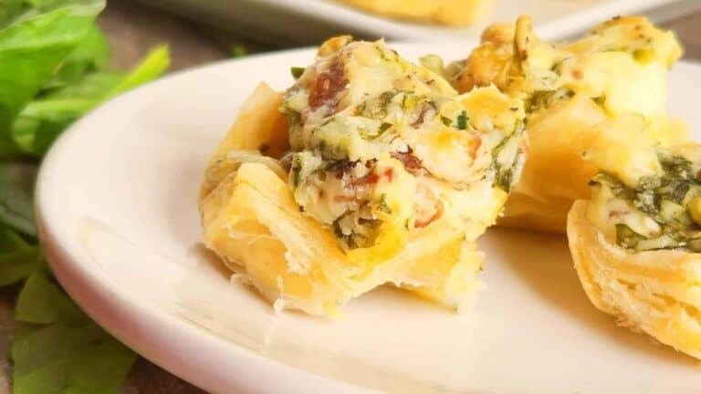 A plate of spinach and cheese tarts on a white plate.