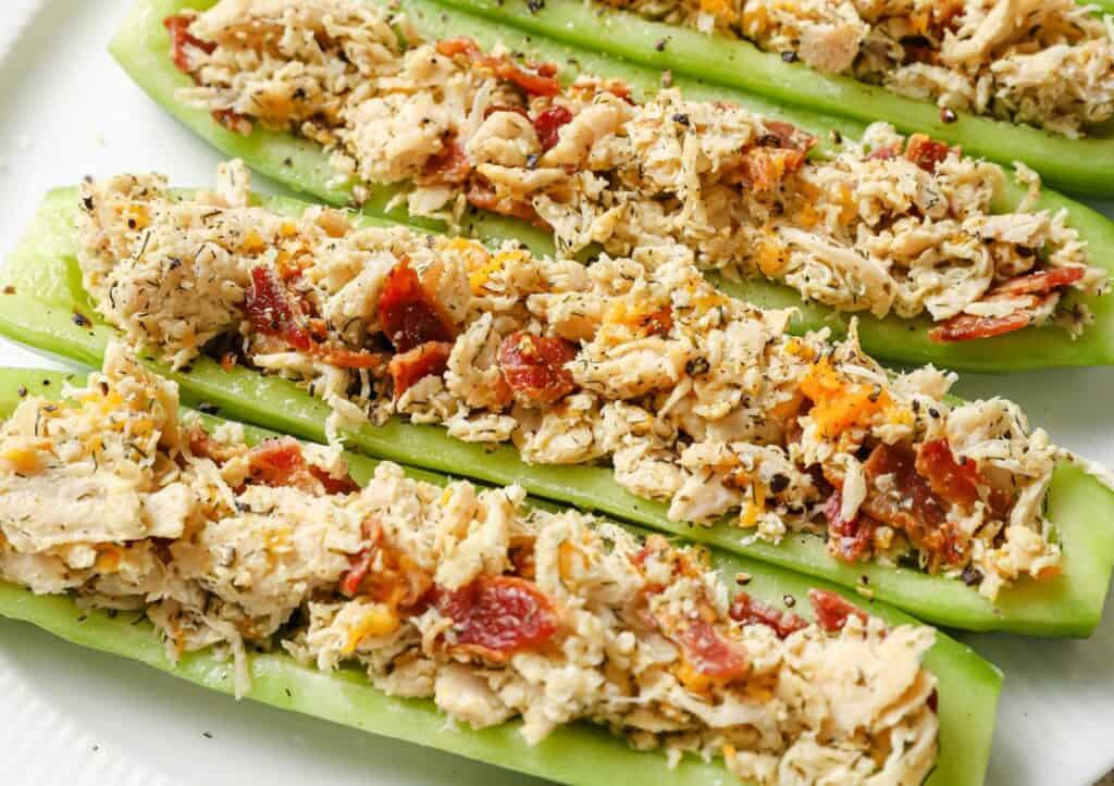 Four stuffed cucumbers on a plate.