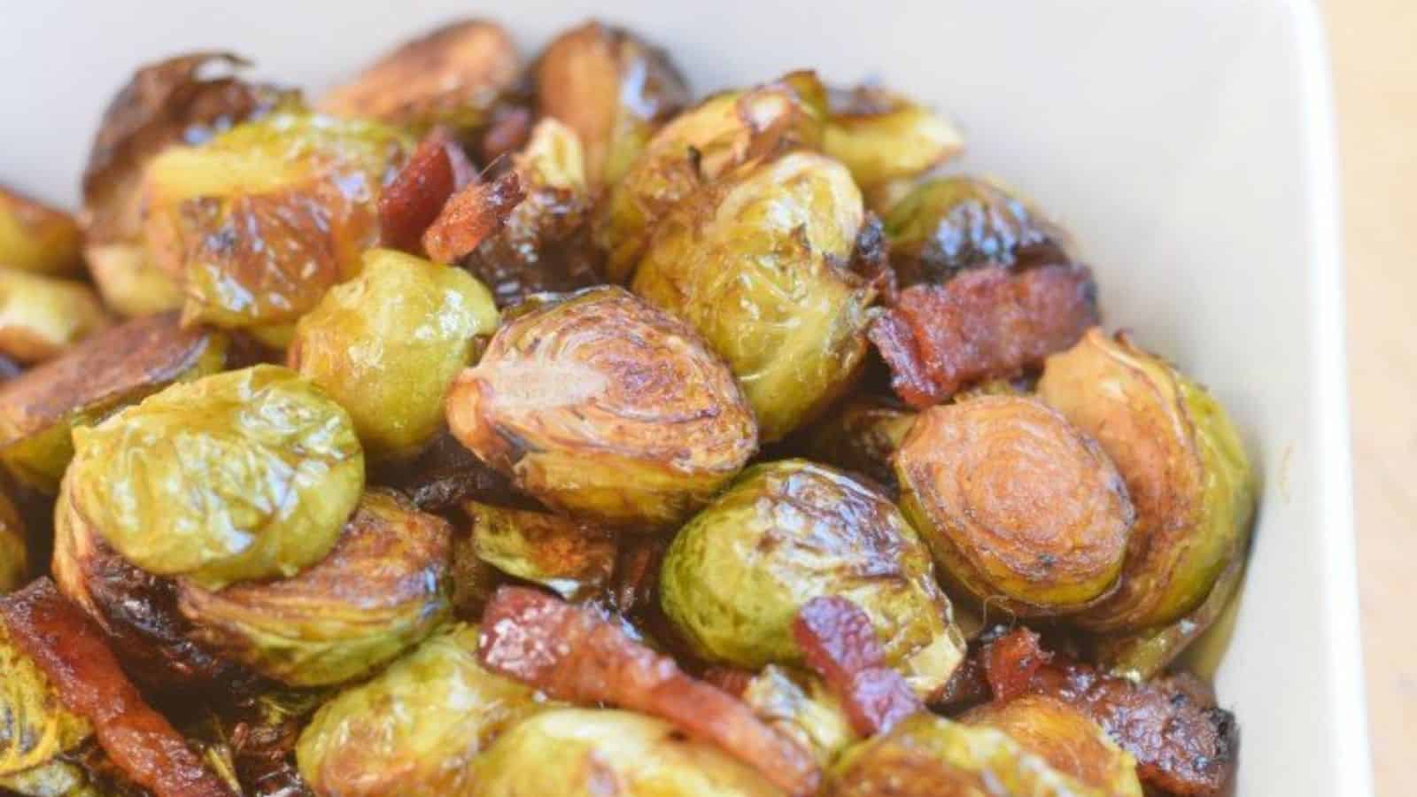 Image shows a close up of Roasted brussels sprouts with bacon in a white bowl.