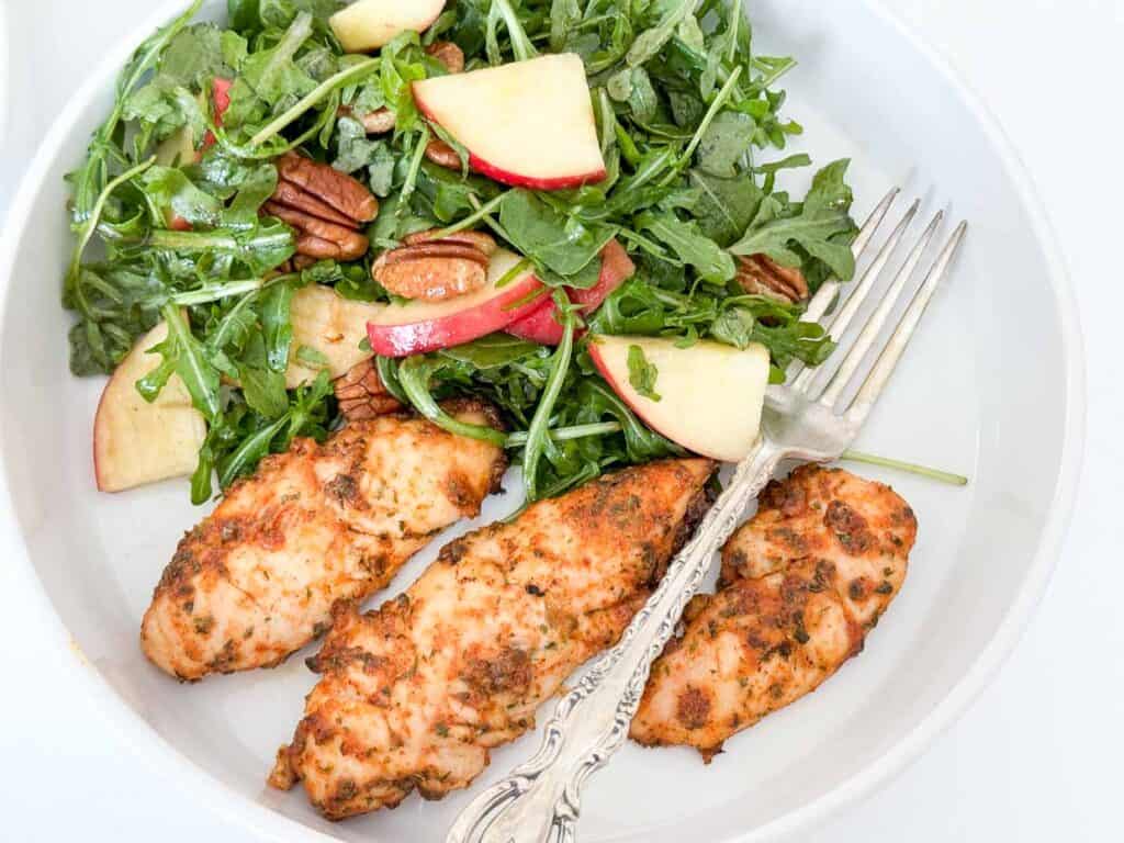 Chicken salad with apples and kale in a white bowl.