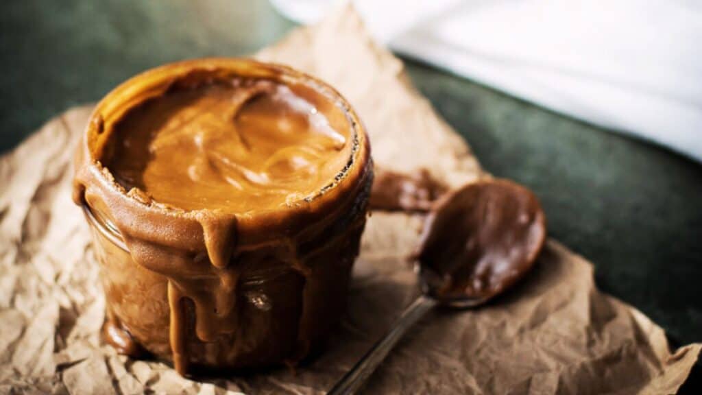 Bourbon butterscotch sauce in a jar with a spoon.