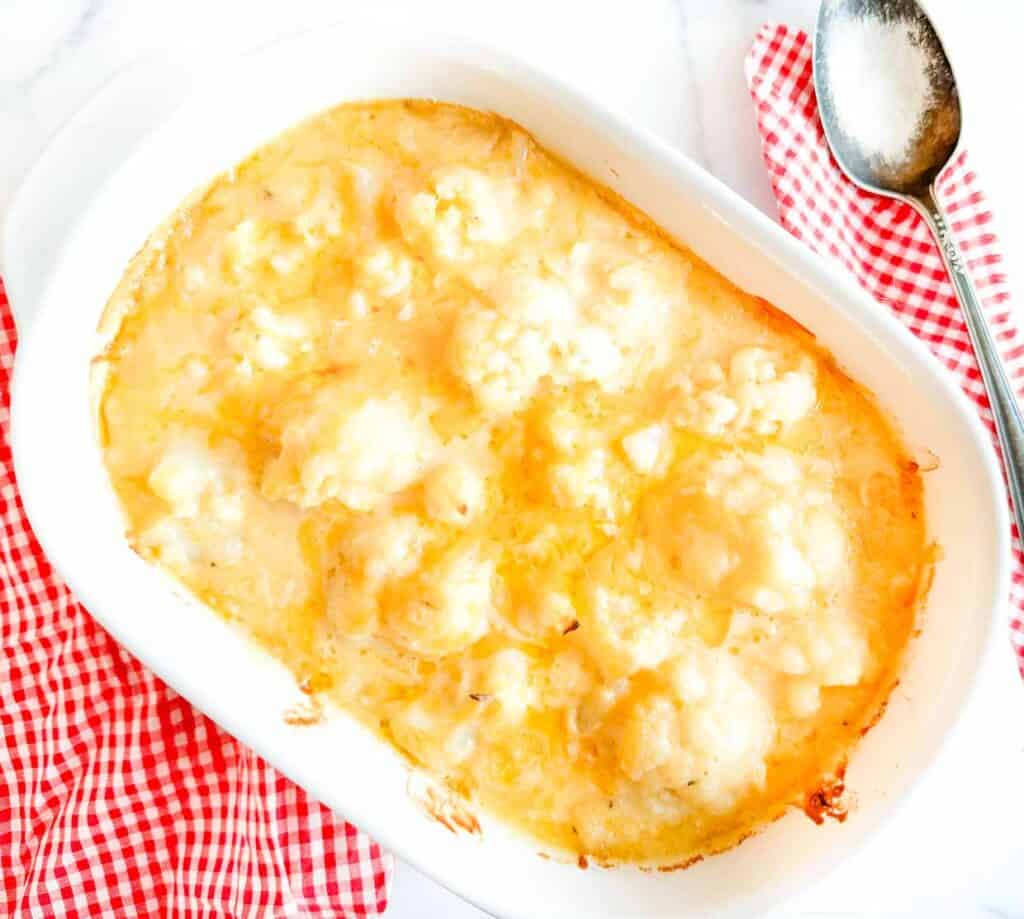 Say cheese! Cheesy cauliflower casserole in a white dish with a spoon.