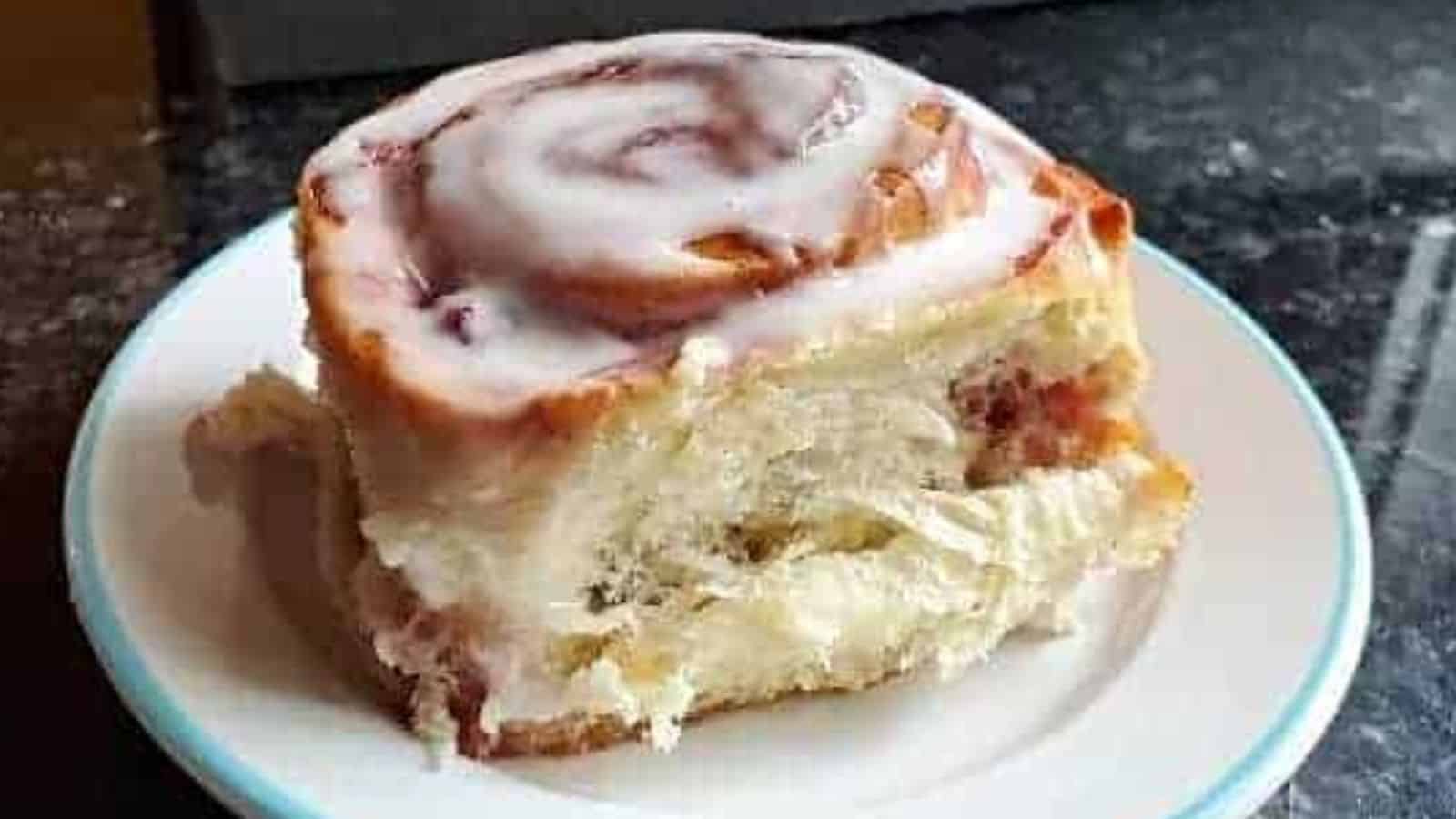 Image shows a closeup of a Cherry Cinnamon Roll on a small plate.