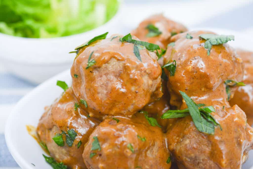 Swedish meatballs in a white bowl with sauce.