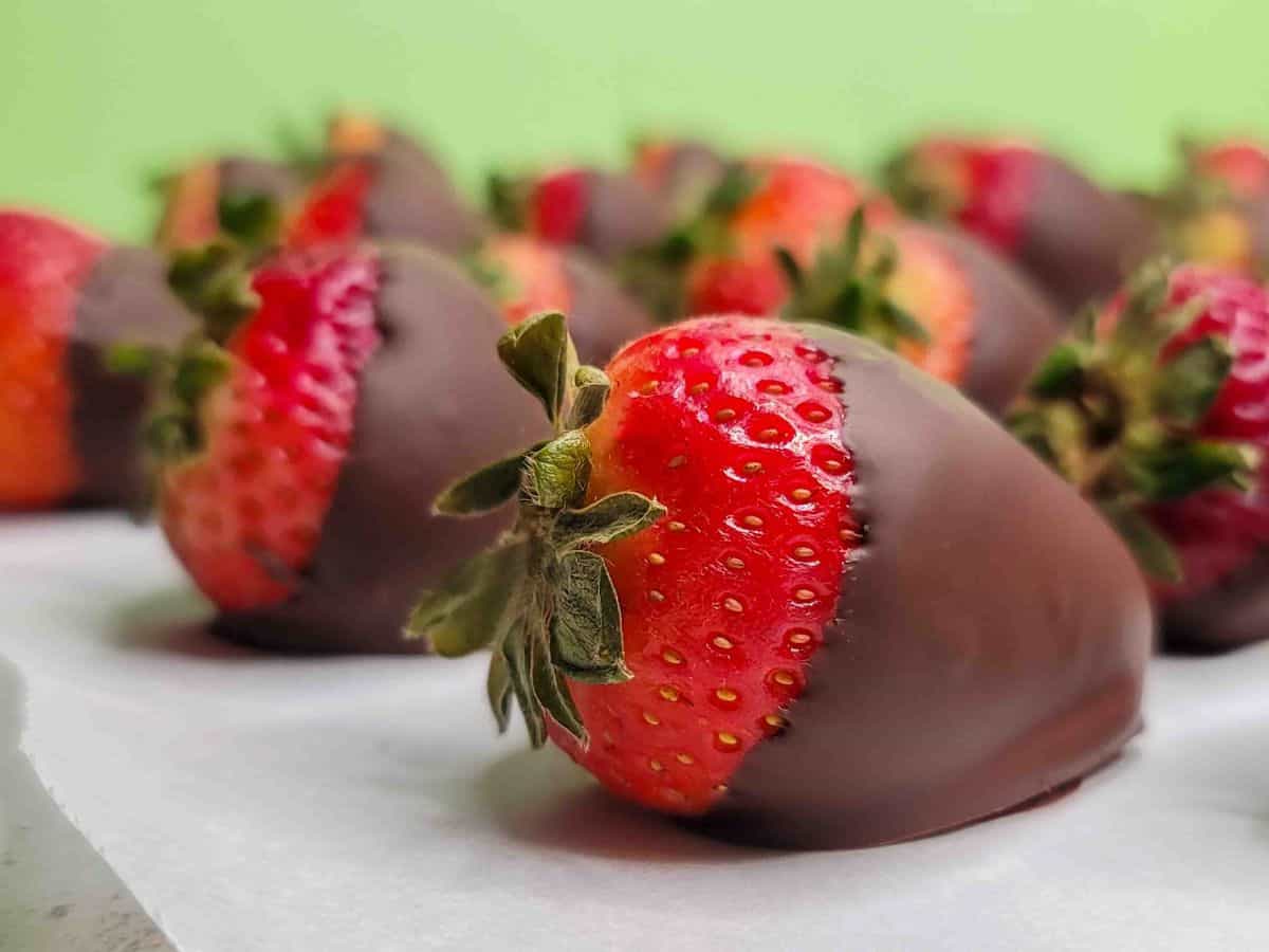 Rows of chocolate covered strawberries on parchment paper.