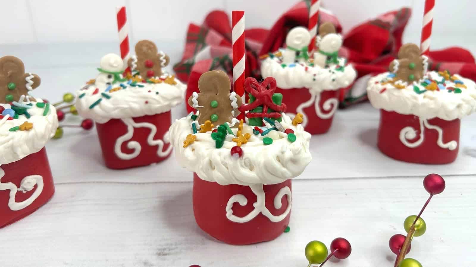 Santa's hat Christmas marshmallow pops on a white table.