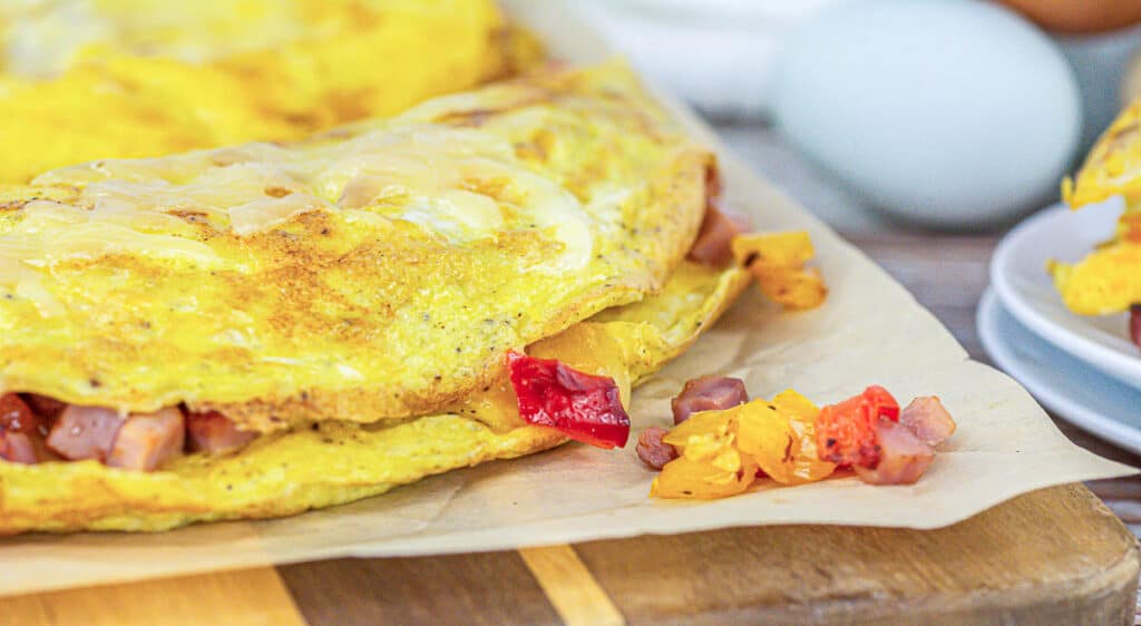 An omelet on a wooden cutting board made with fresh ingredients from a small batch.