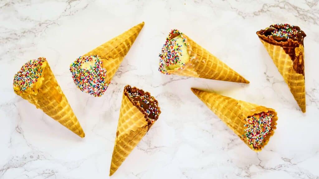 Ice cream cones with sprinkles on a marble surface.