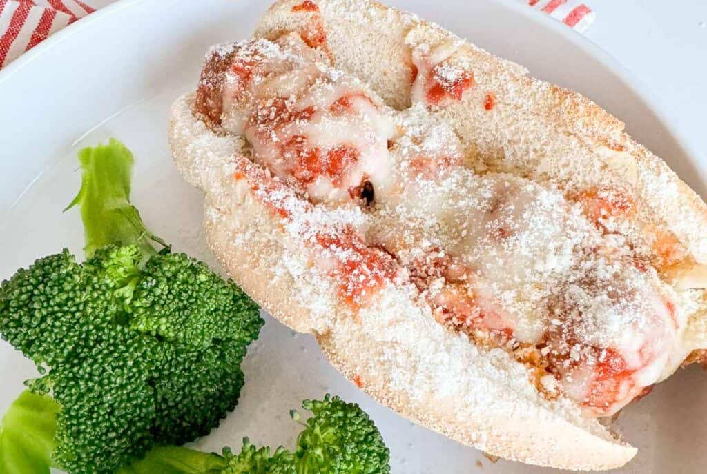 Say cheese while enjoying a hot dog with cheese and broccoli on a plate.