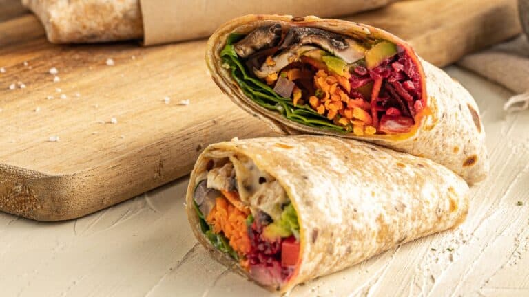 A Vegan Veggie Wrap on top of a cutting board.