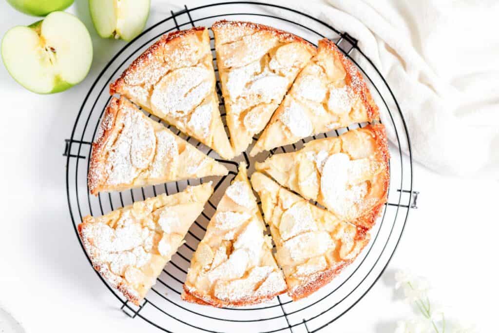 A slice of apple cake on a cooling rack.