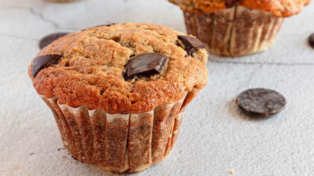 A muffin with chocolate pieces on it.