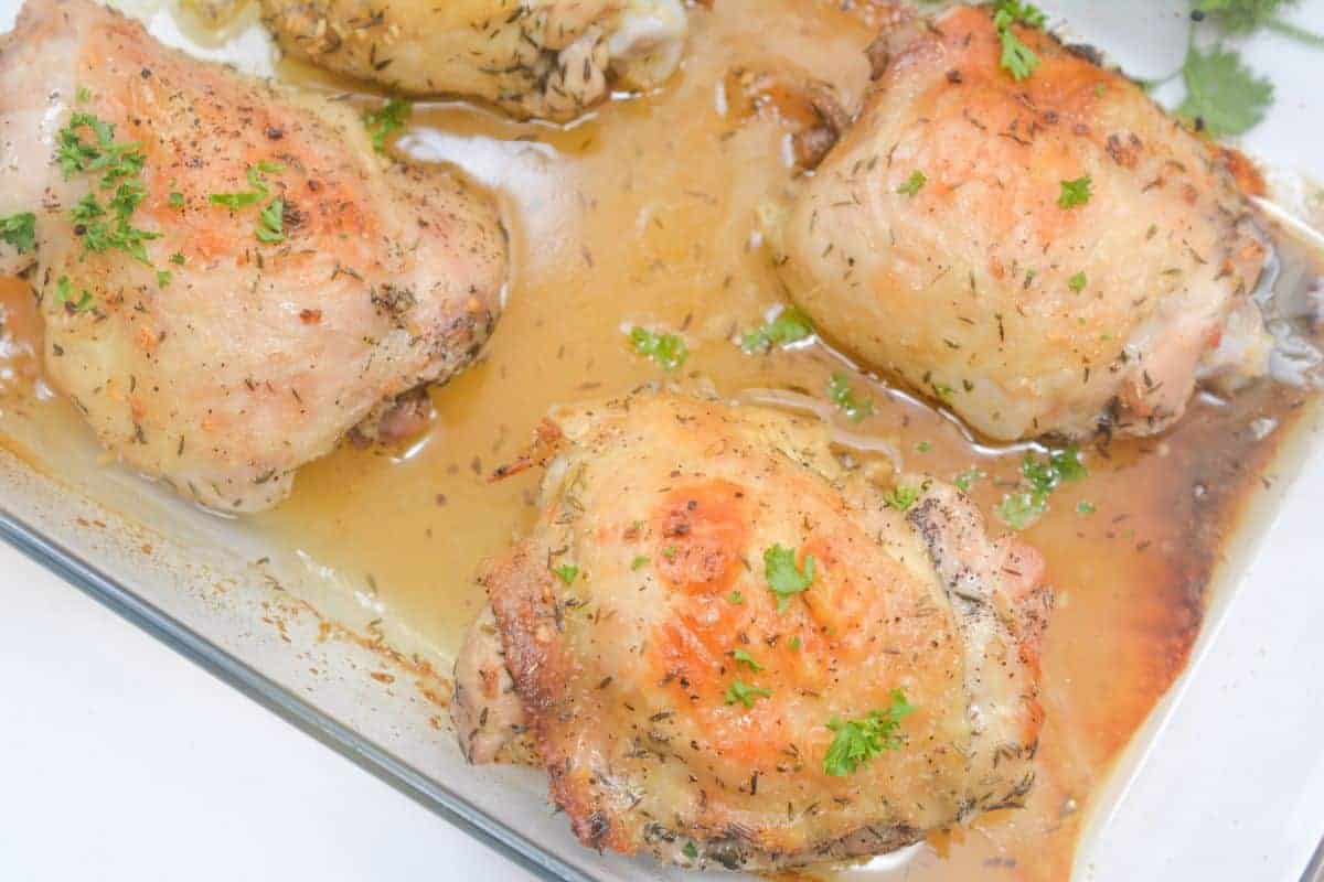 Honey and lemon baked chicken thighs with parsley on top in a baking dish.