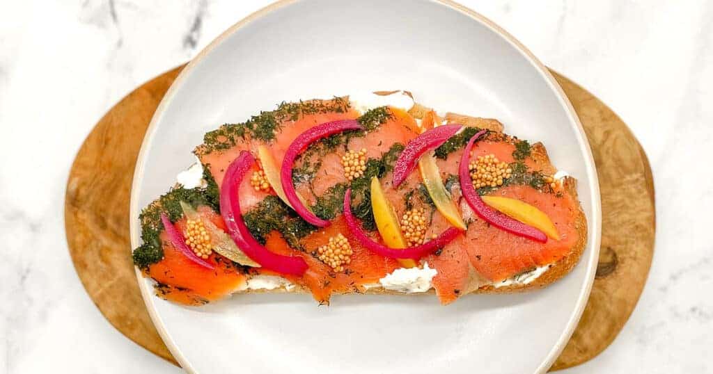 A slice of bread with smoked salmon and arugula.