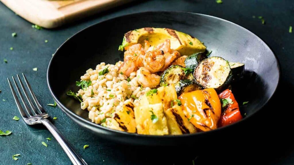 A black bowl with grilled vegetables and rice.