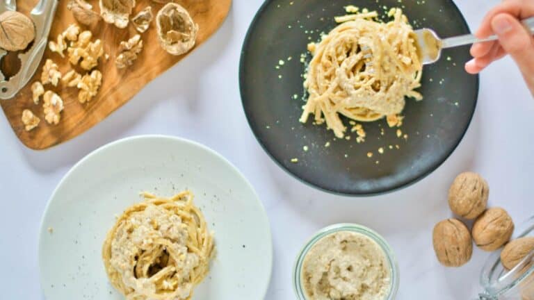 A plate of pasta with walnuts on it.