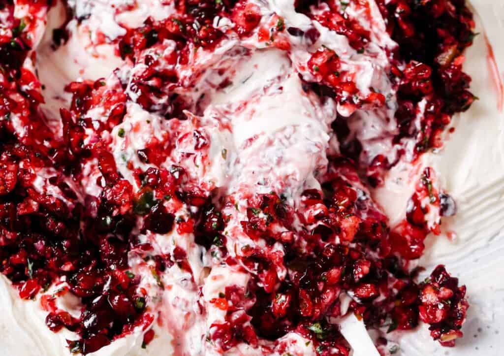 A bowl of cream cheese and cranberries on a white plate.