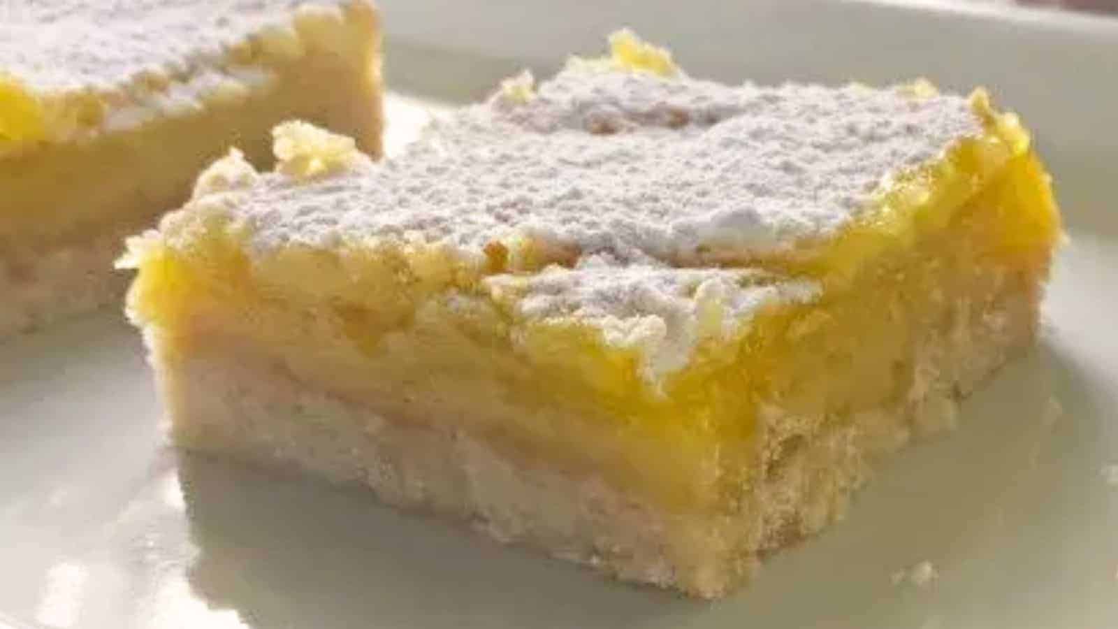 Image shows a close up of Lemon Squares on a white plate.