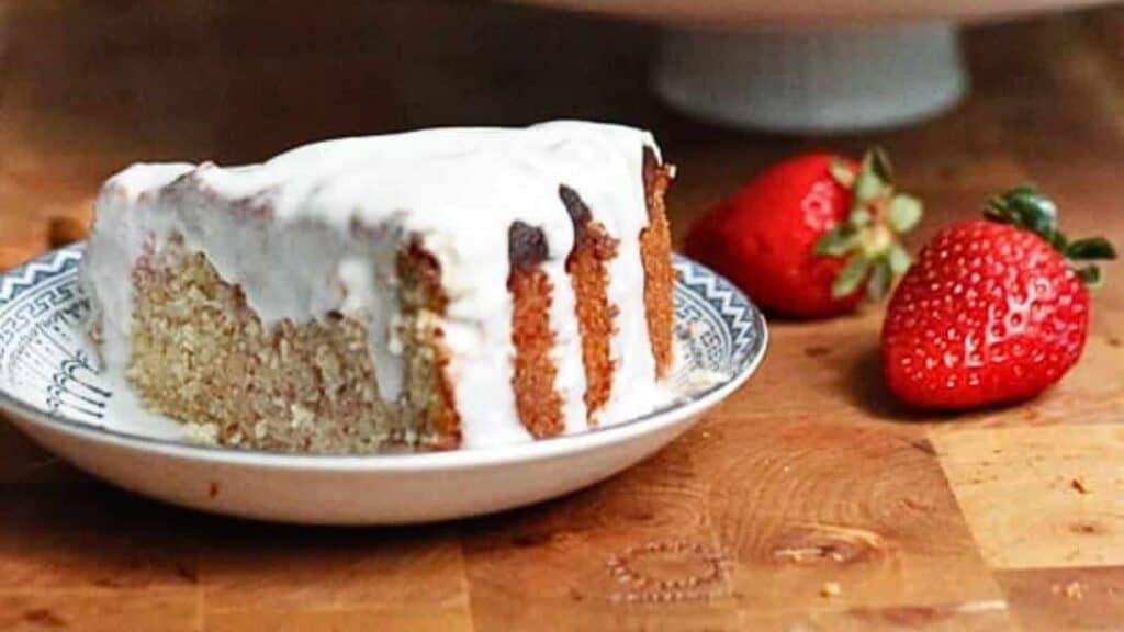 A slice of lemon almond yogurt cake with icing on a plate.